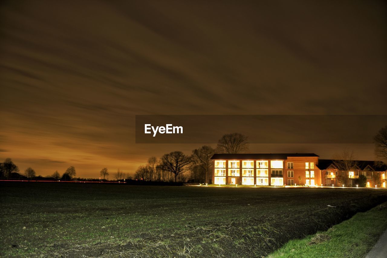 BUILDING ON FIELD AGAINST SKY DURING SUNSET