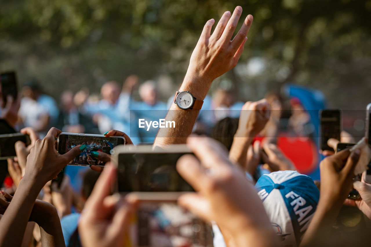 Cropped hands of crowd photographing through mobile phones