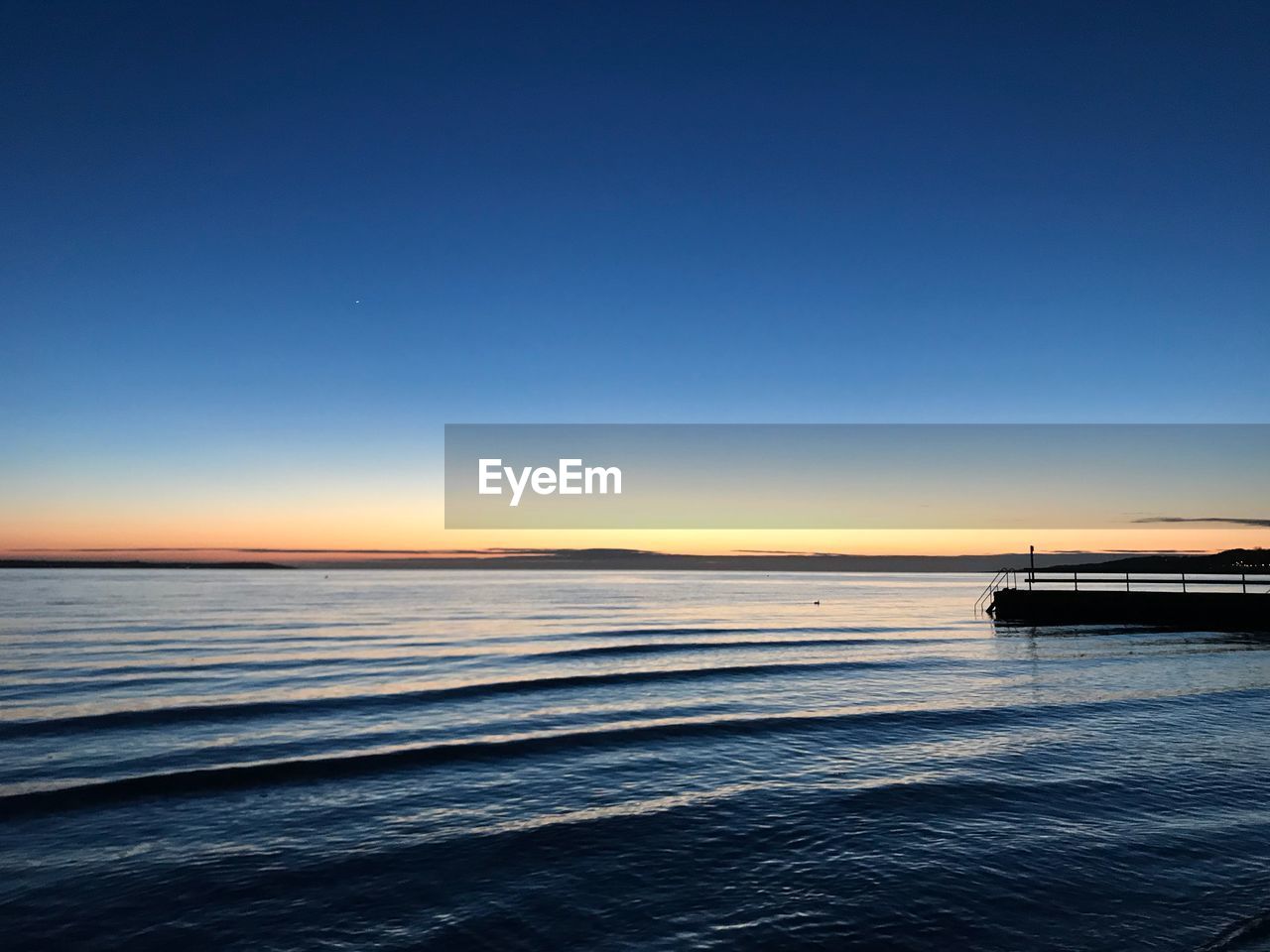 Scenic view of sea against clear sky at sunset