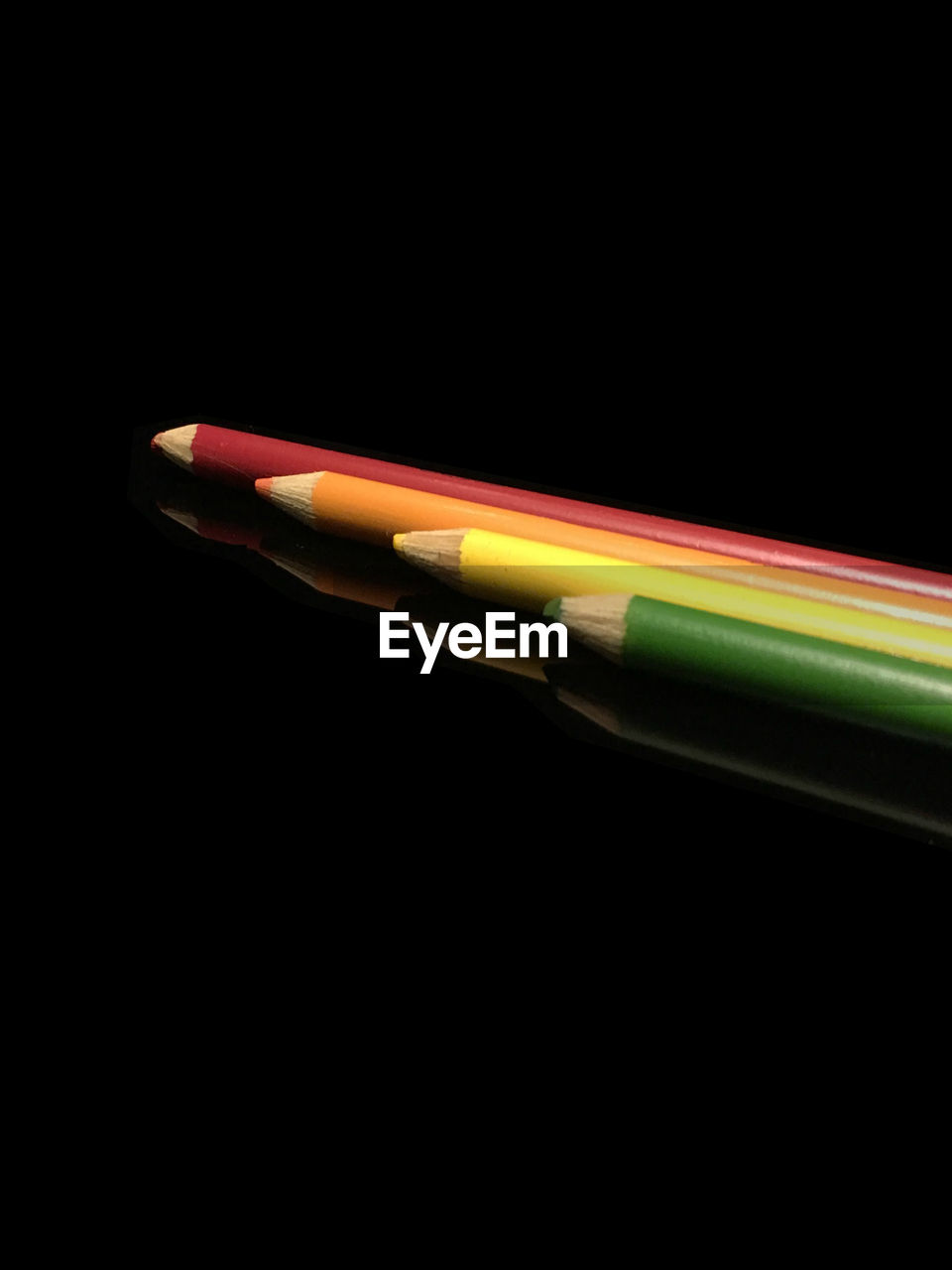 Close-up of colored pencils over black background