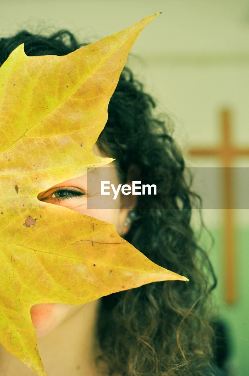Woman covering face with yellow leaf