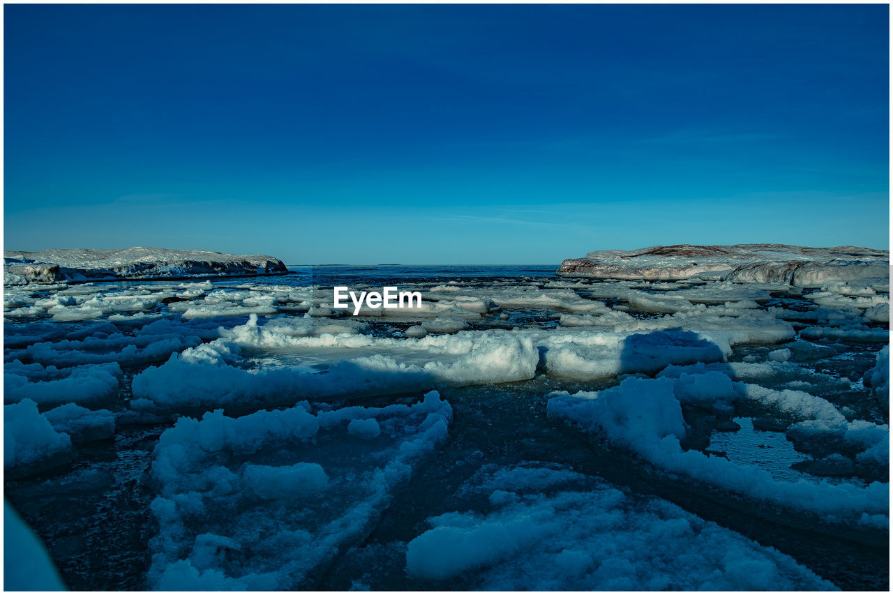 FROZEN LANDSCAPE AGAINST BLUE SKY