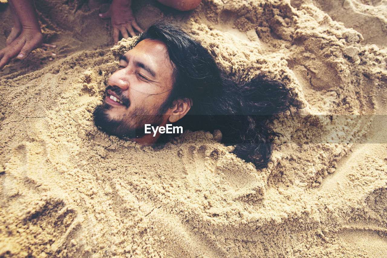 High angle view of man buried in sand at beach