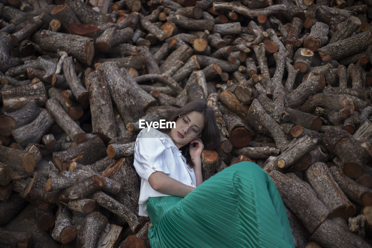 Woman with melancholic and romantic vintage clothes leaning on wooden logs