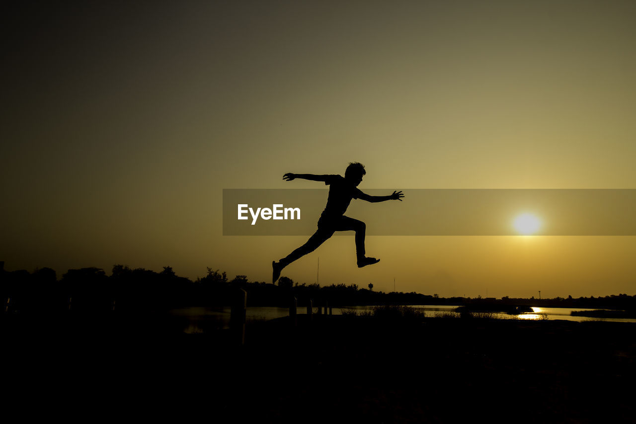 Silhouette man jumping against sky during sunset