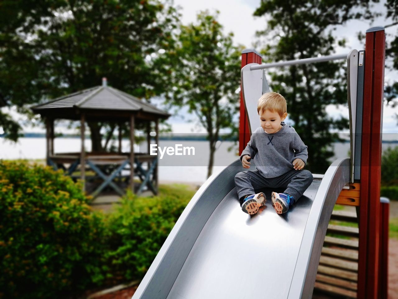 Portrait of boy sitting on slide at playground