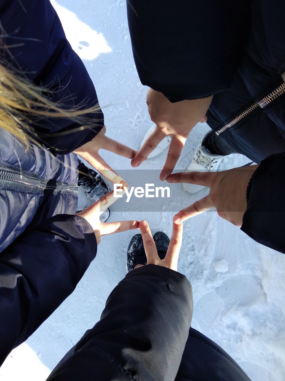 Low section of people making star shape over snowy field