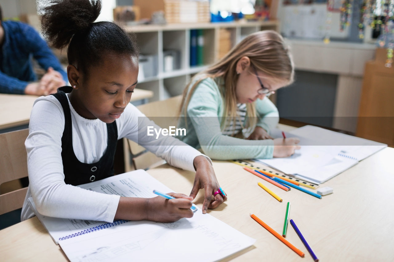 Schoolgirls studying at desk in classroom