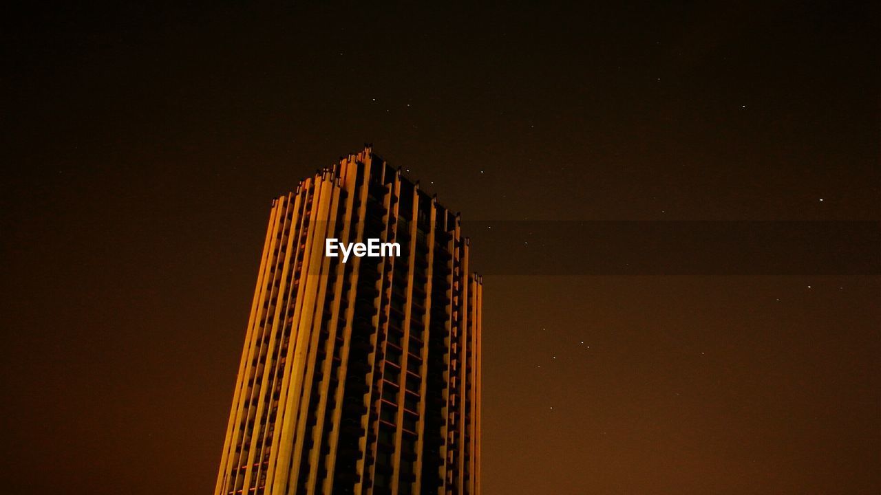 High section of illuminated building against sky at night