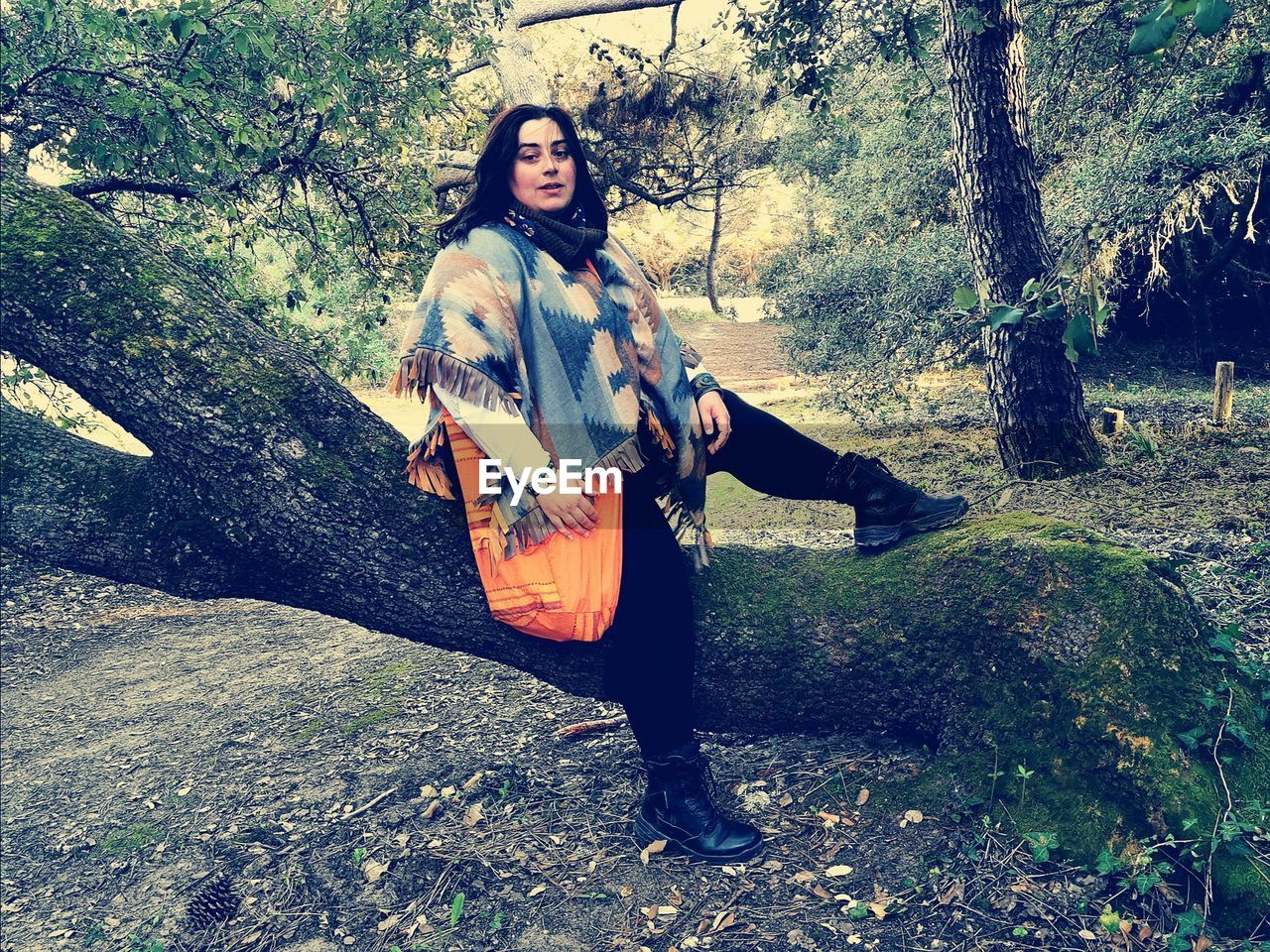 FULL LENGTH PORTRAIT OF YOUNG WOMAN SITTING ON LAND