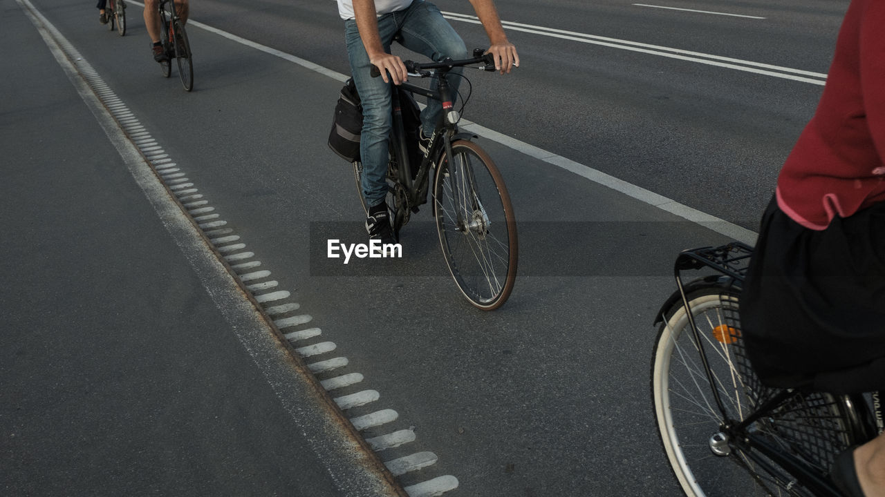 LOW SECTION OF MEN RIDING BICYCLE ON ROAD