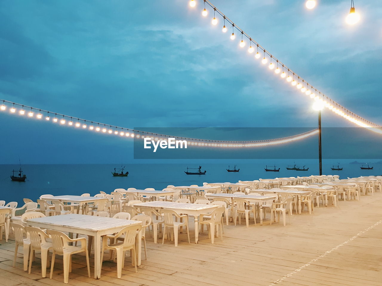 The romantic evening dining place decorated with the warm lamps and sea view
