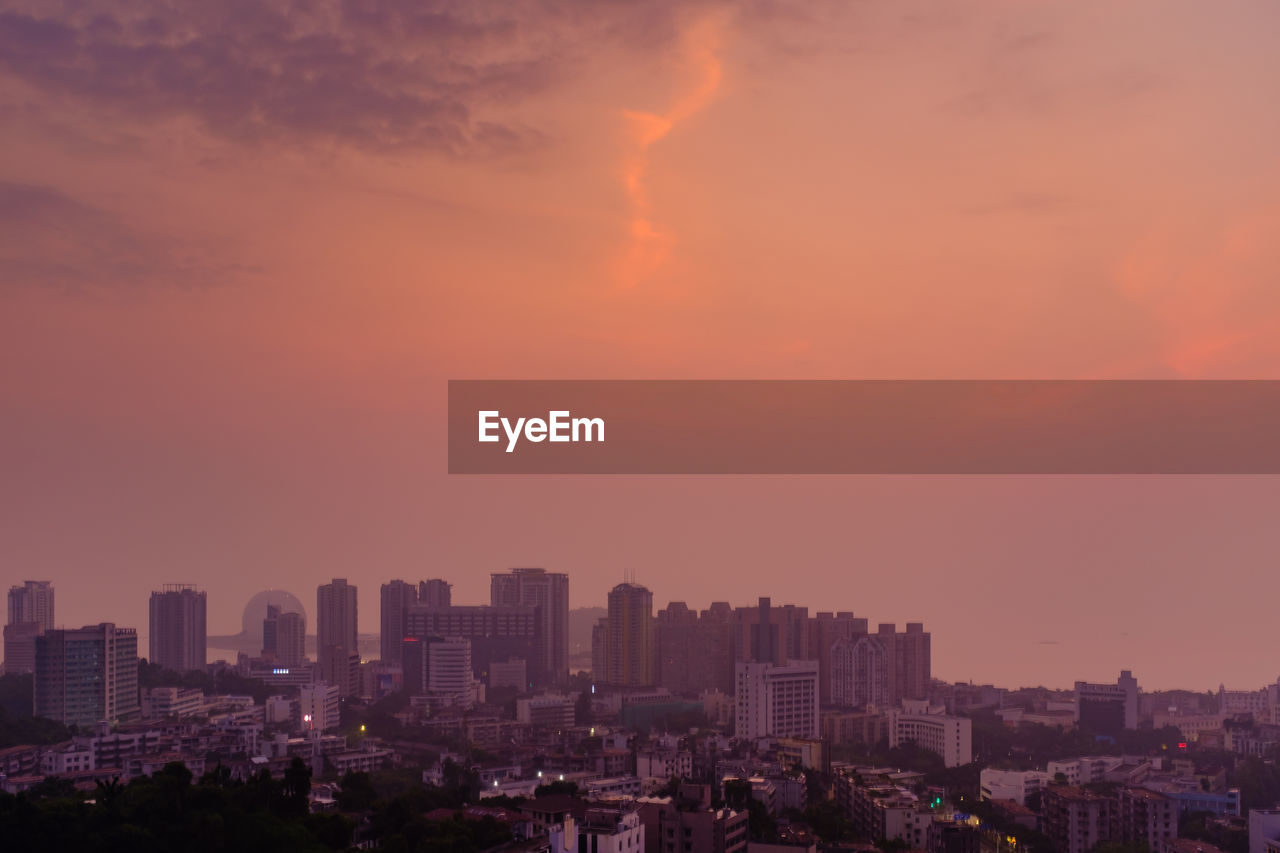 Aerial view of buildings in city against sky during sunset