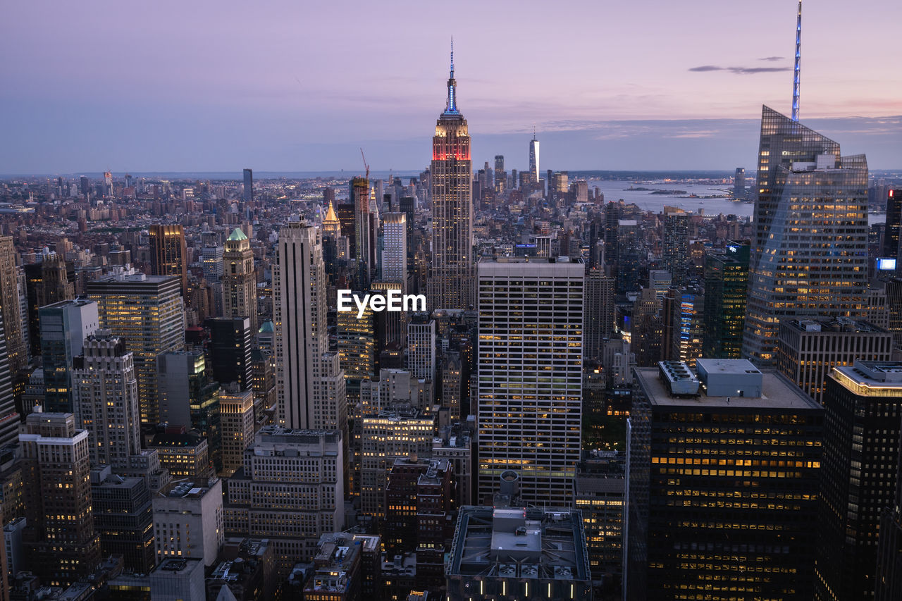 Aerial view of illuminated buildings in city against sky during sunset