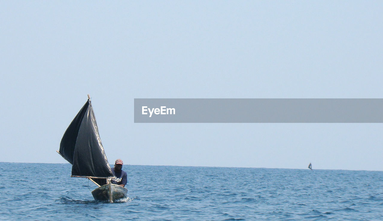 MAN IN SEA AGAINST SKY