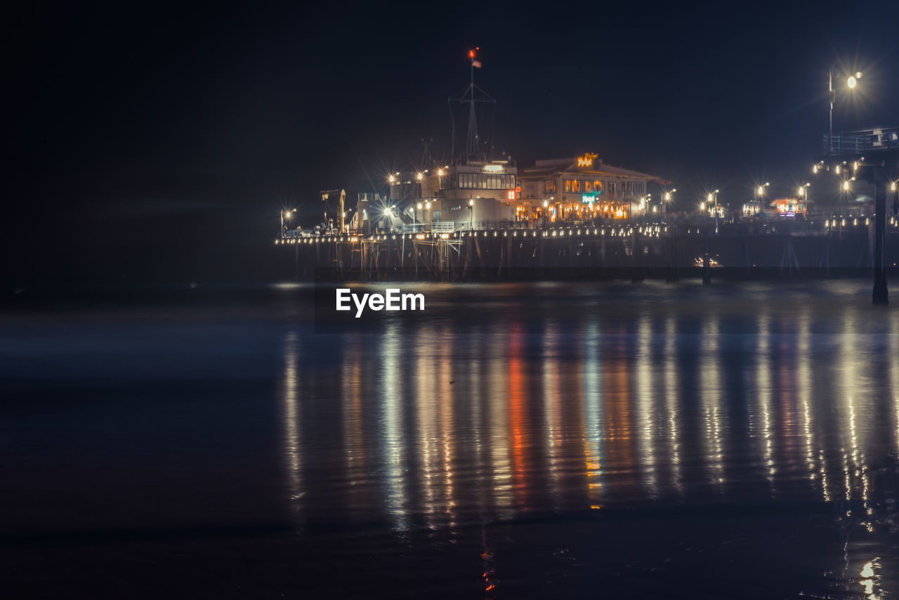 REFLECTION OF ILLUMINATED LIGHTS IN WATER AT NIGHT