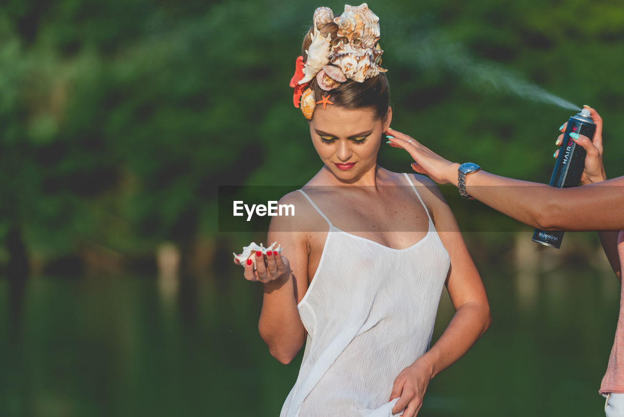 YOUNG WOMAN WITH UMBRELLA STANDING AGAINST WHITE WALL