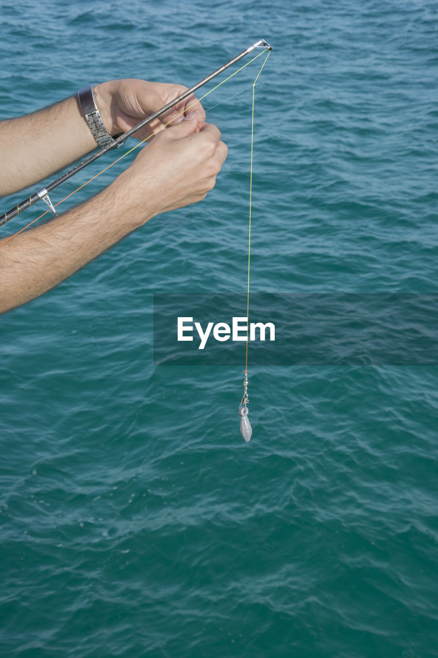 Cropped hands of man fishing in sea