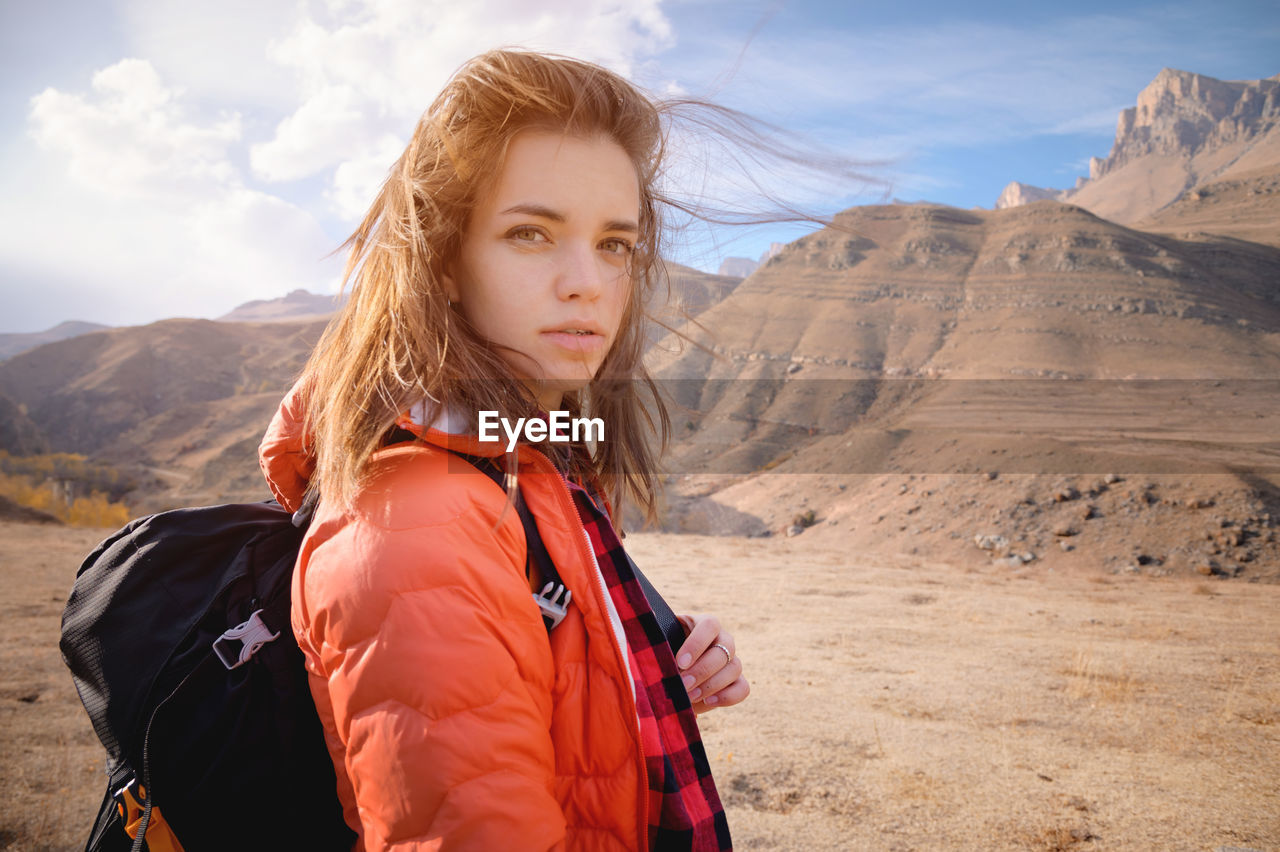 Young attractive jewish woman in a down jacket and with a backpack against the backdrop