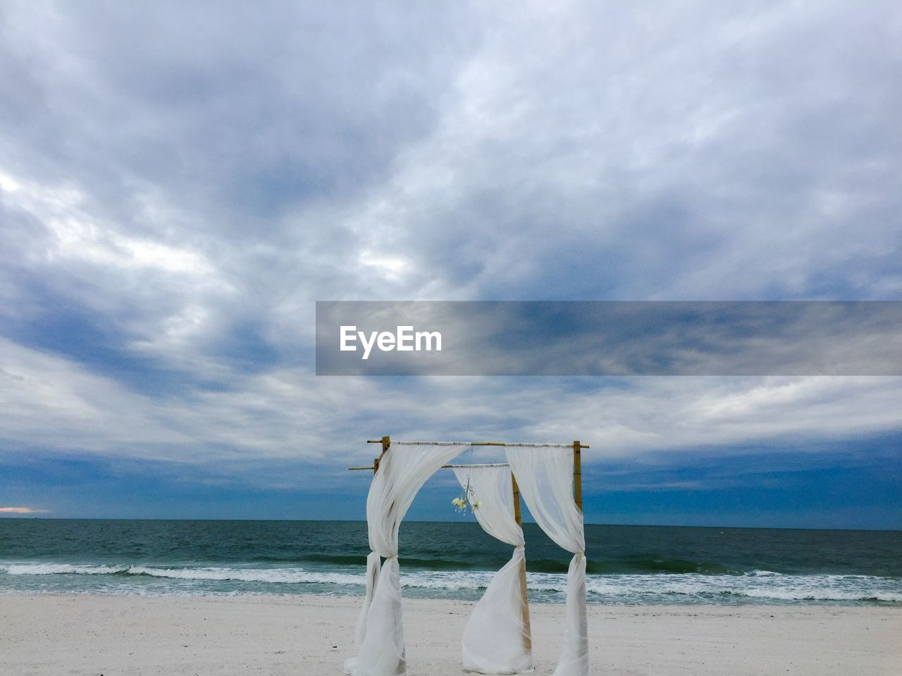 Entertainment tent on beach against cloudy sky