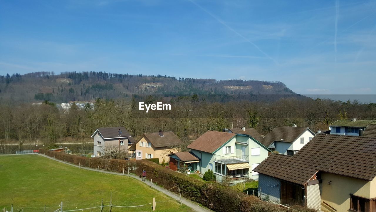 HIGH ANGLE VIEW OF HOUSES AND TREES AGAINST SKY