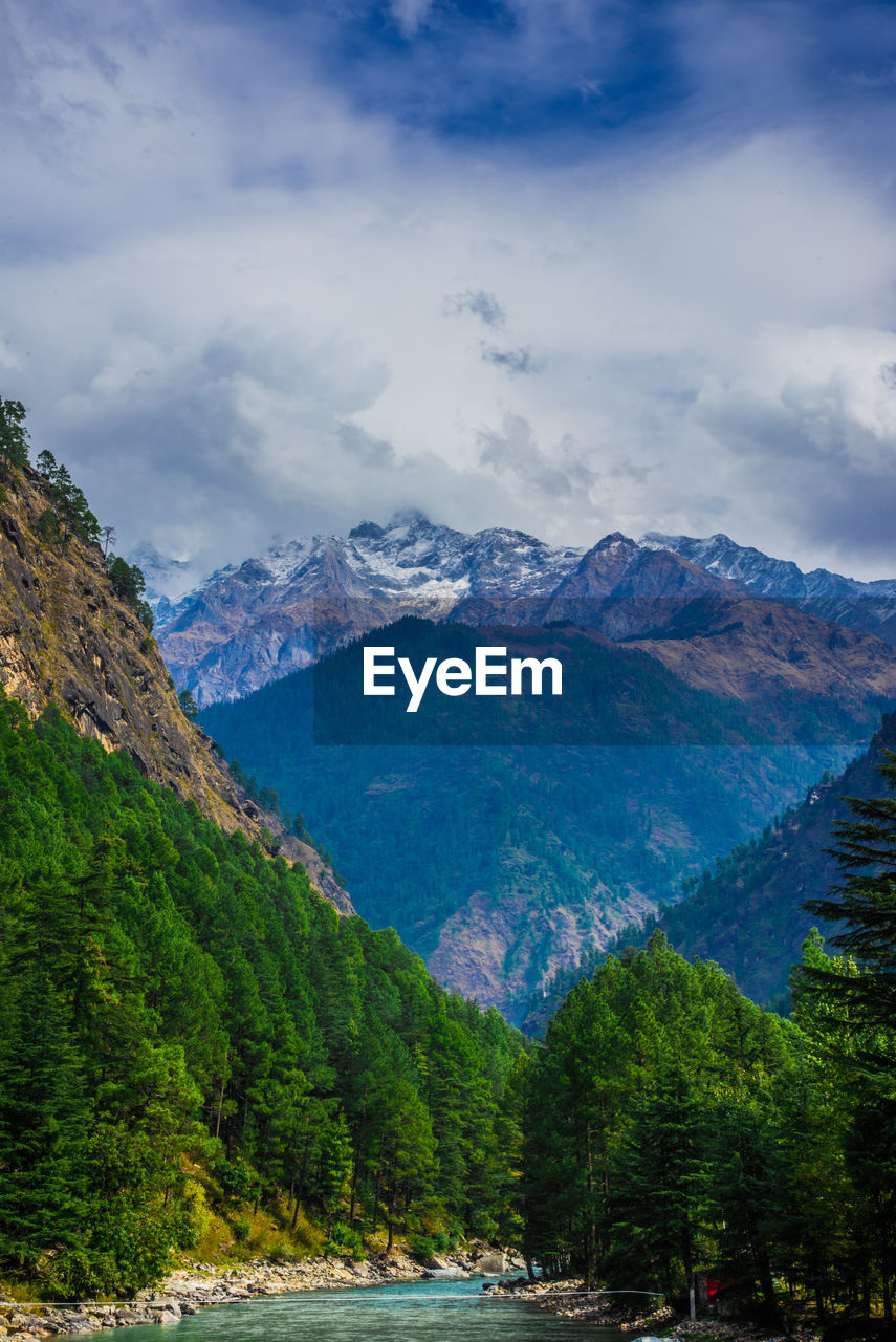 Scenic view of river and mountains against cloudy sky