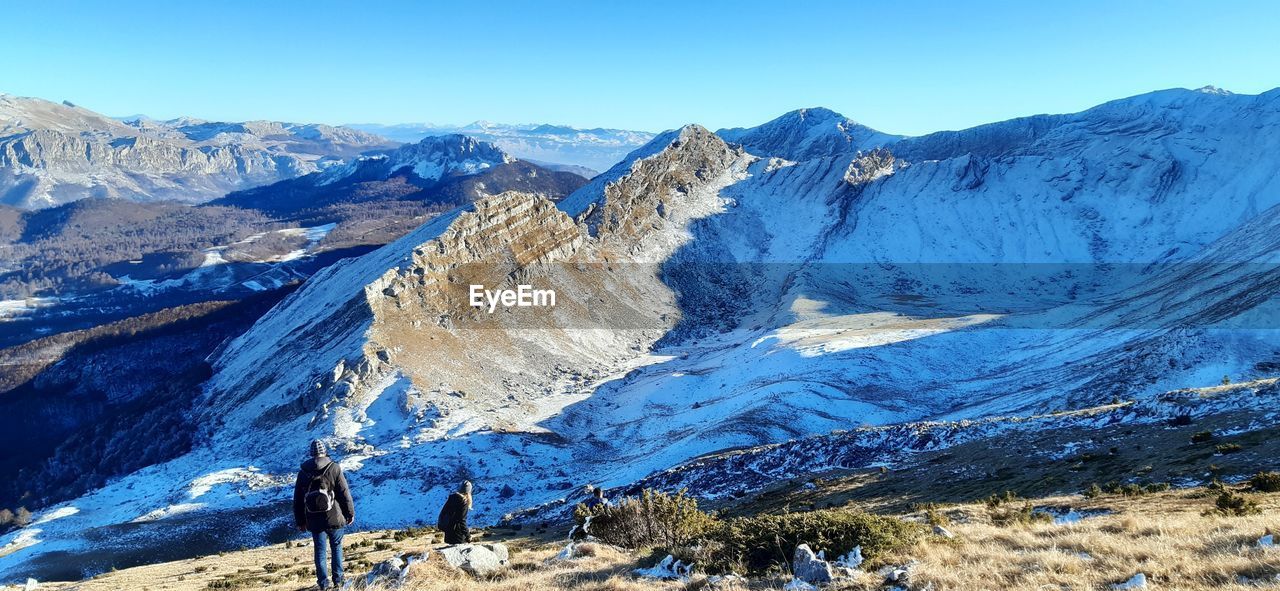 Panoramic view of snowcapped mountains against clear blue sky