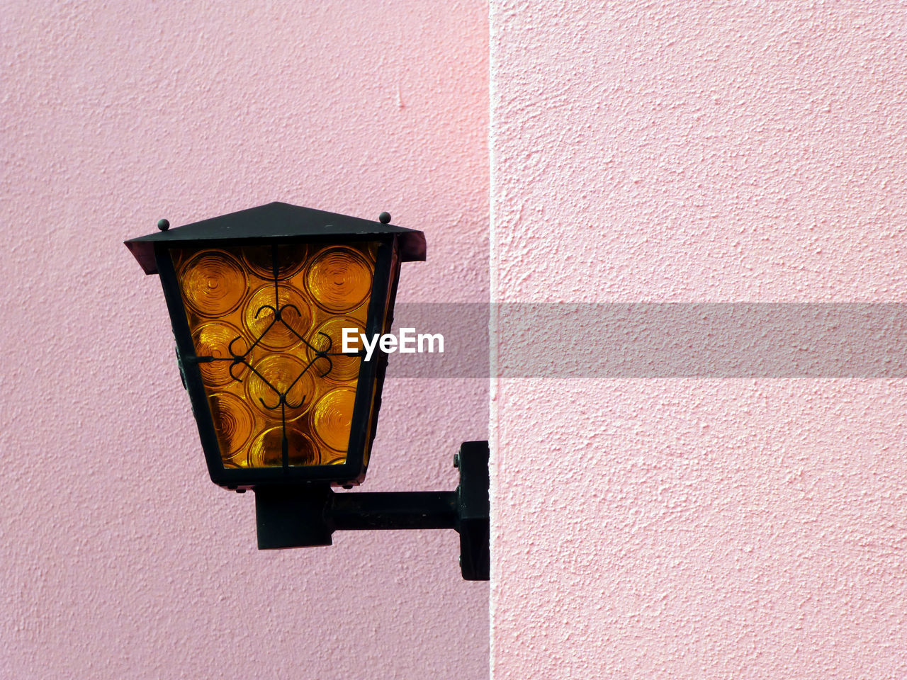 Charming view of the amber-black lamp against a light pink wall