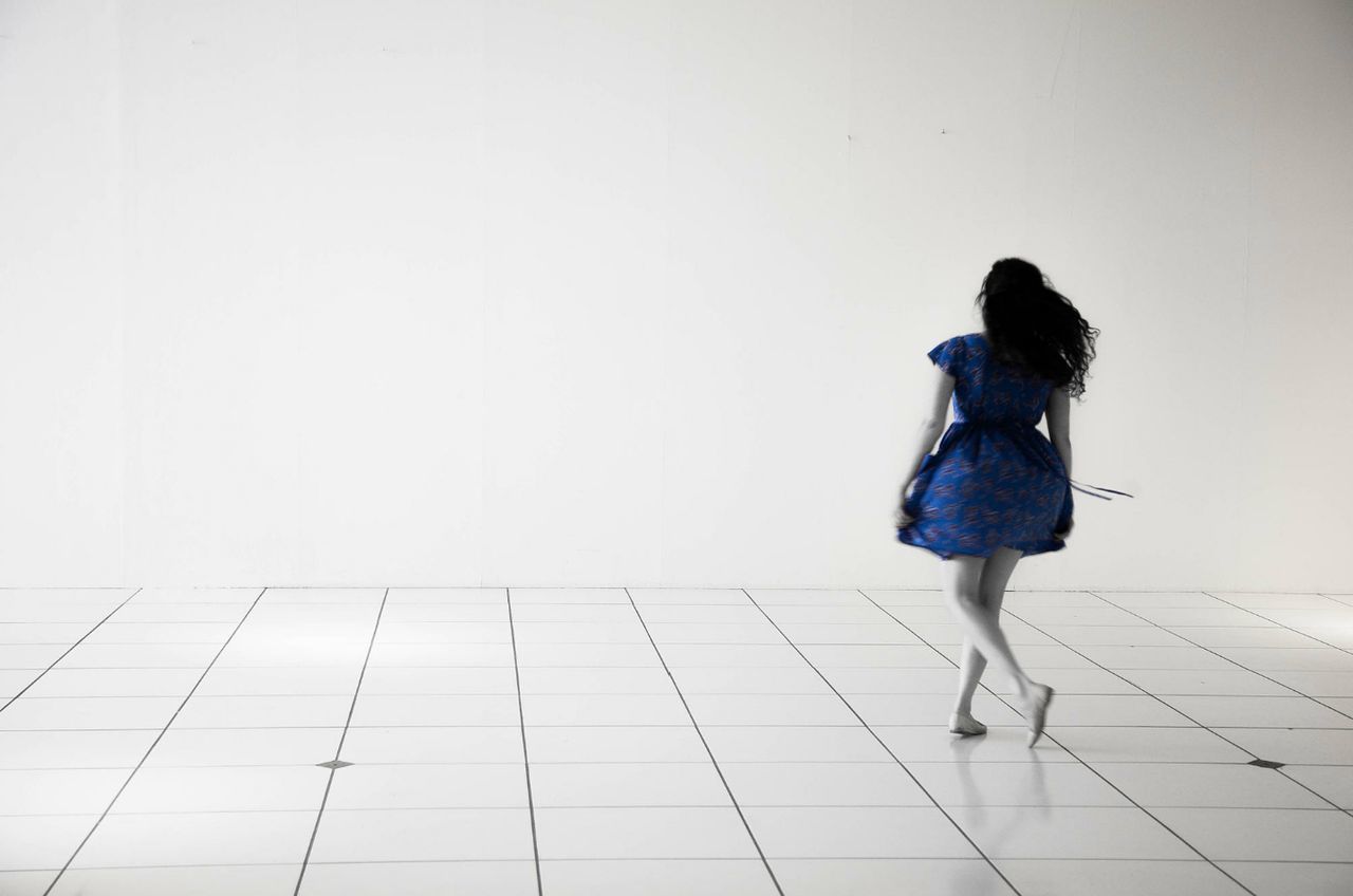 REAR VIEW OF WOMAN STANDING ON TILED FLOOR