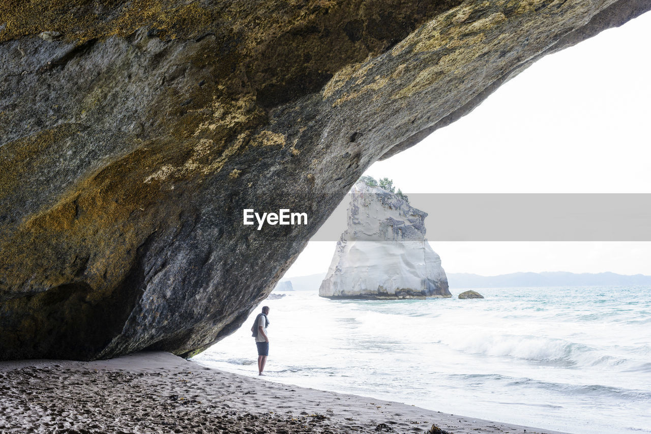 Man standing by rock formation at beach