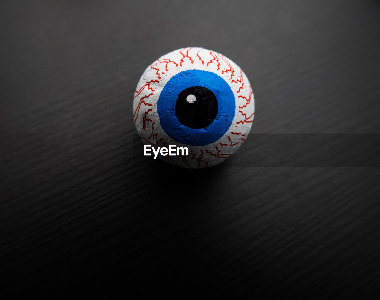 Funny halloween treat - candy eyeball on dark background. copy space.