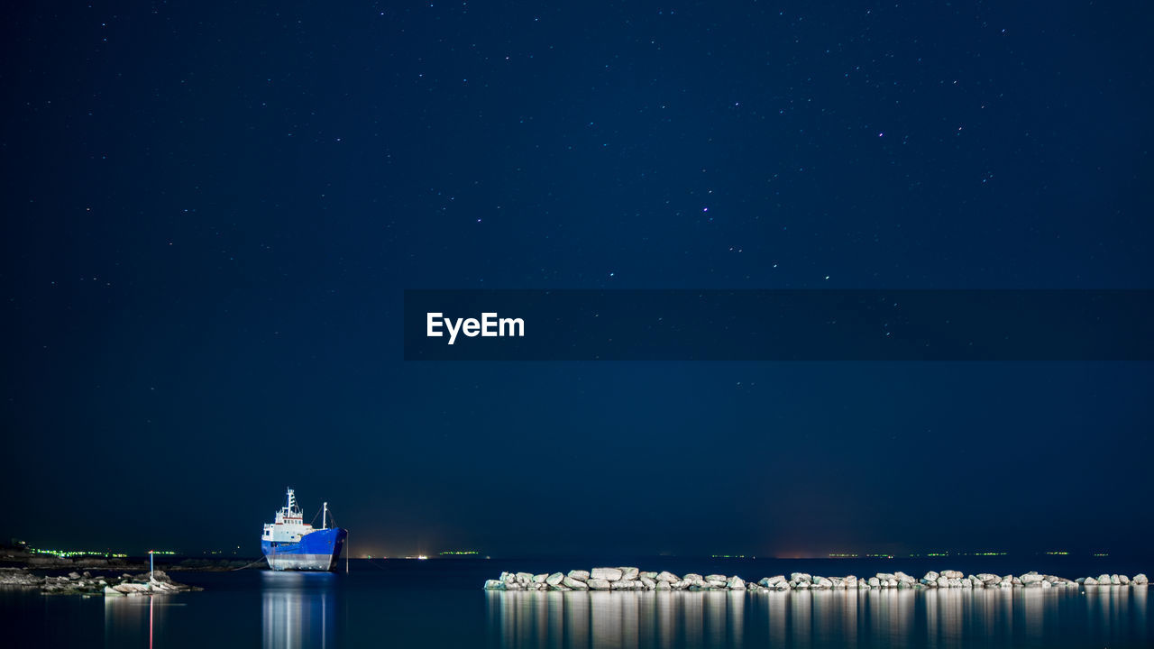Ship sailing on sea against sky at night