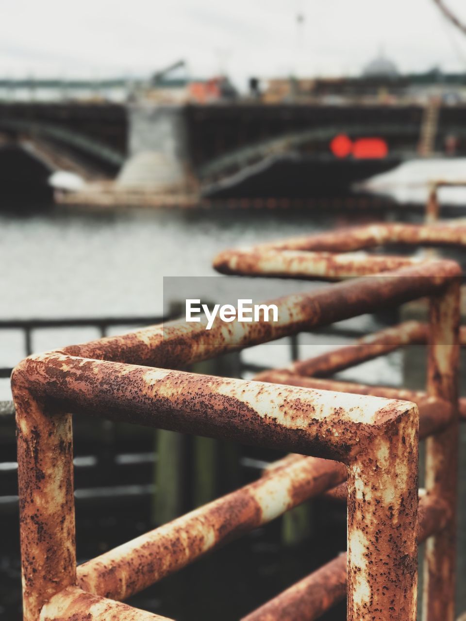 Close-up of rusty railing against bridge over river