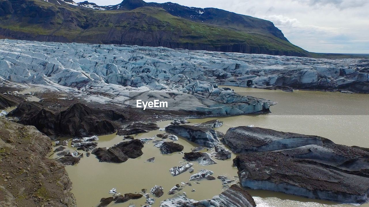 Scenic view of river by mountains against sky