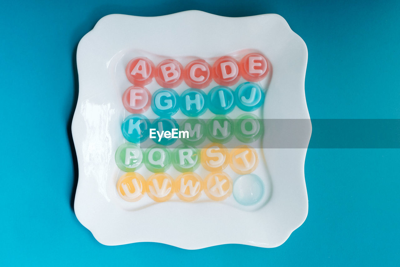 Directly above shot of alphabets in plate over blue background