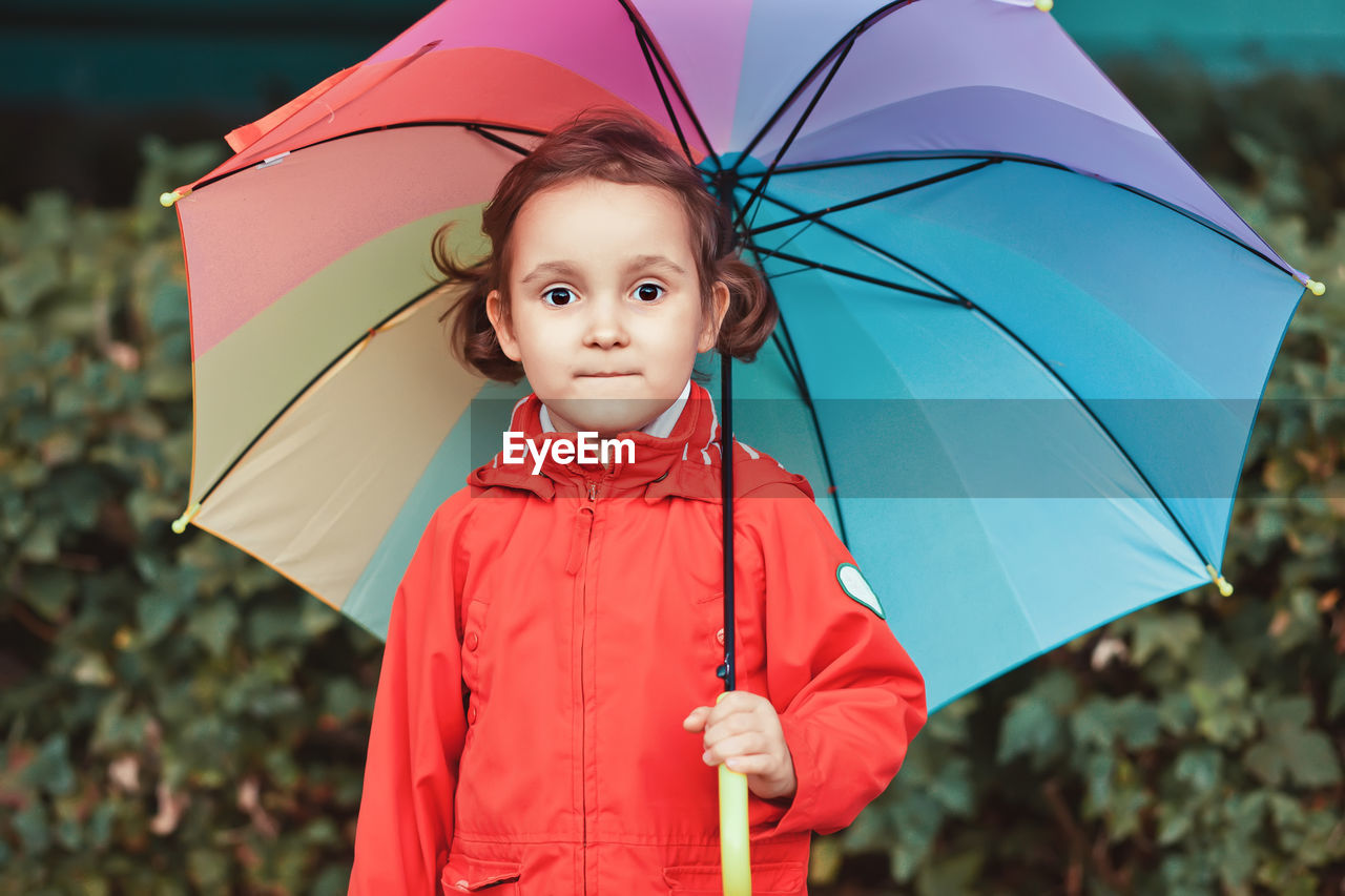 Portrait of cute girl standing in rain during rainy season