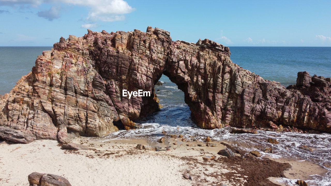 ROCK FORMATIONS ON SHORE AGAINST SKY