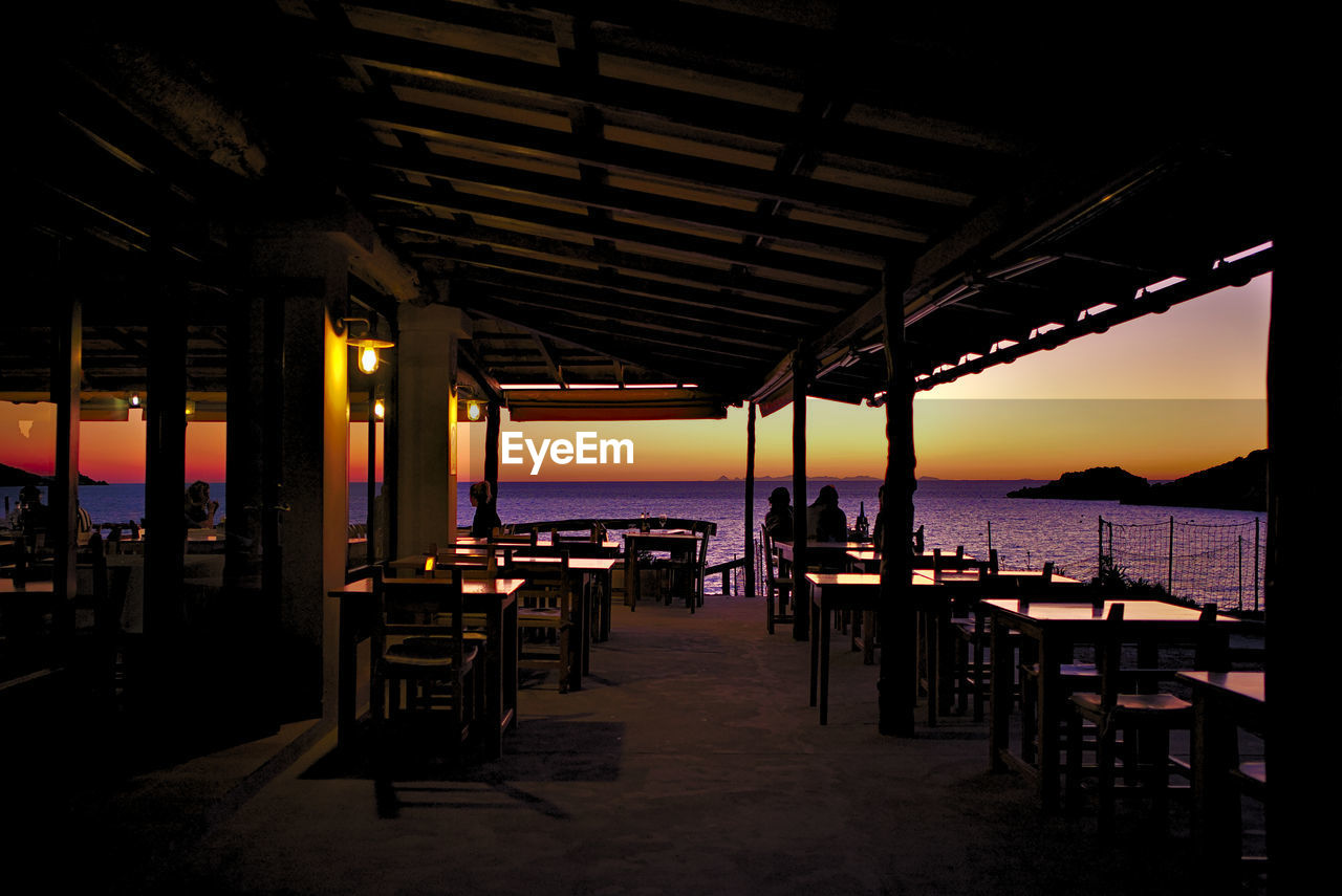 EMPTY CHAIRS AND TABLES AT RESTAURANT AGAINST SKY