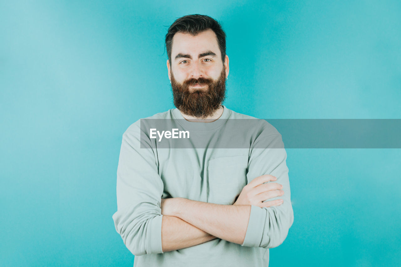 portrait of young man against turquoise background