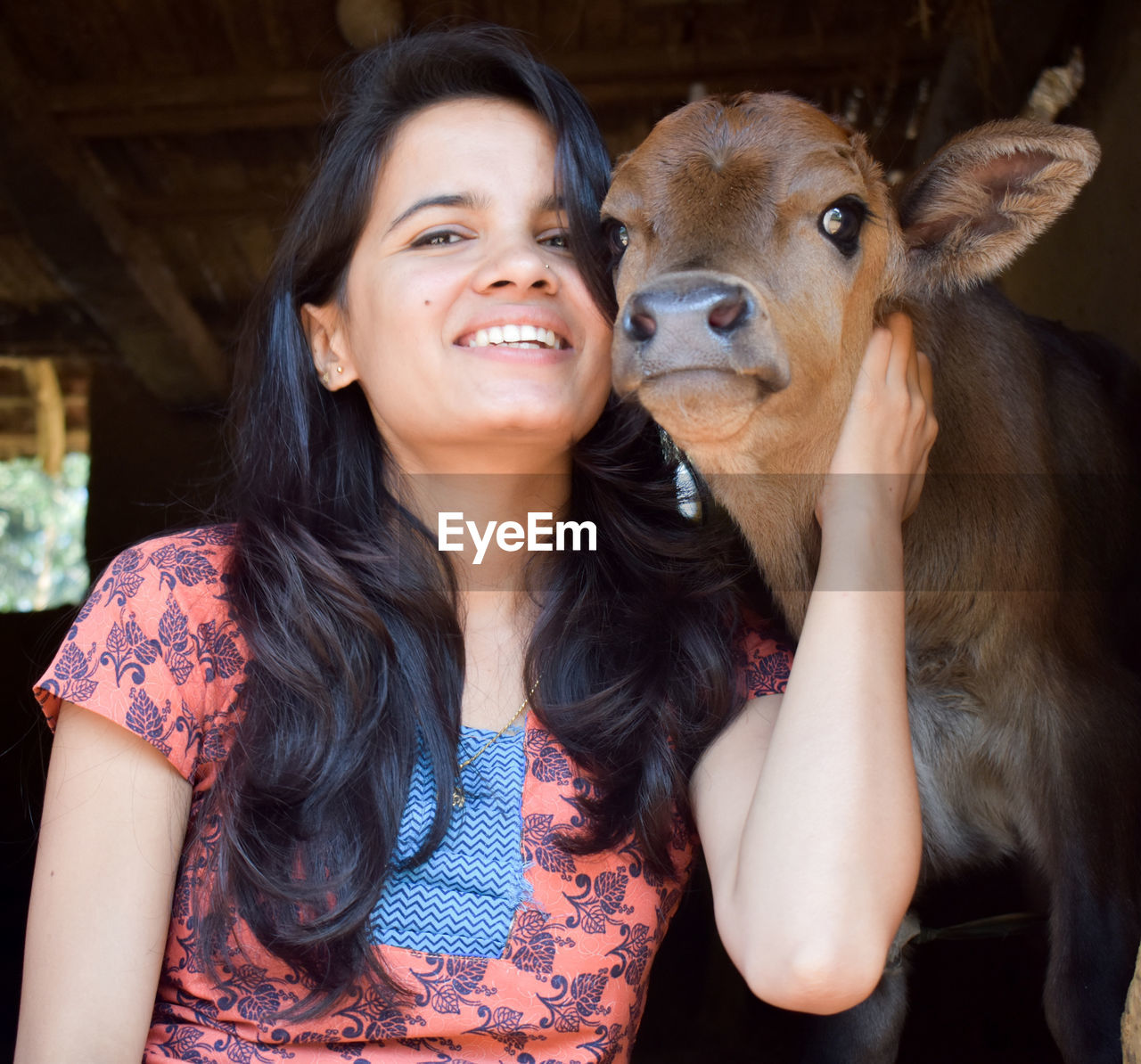 Portrait of smiling young woman and new born cattle 