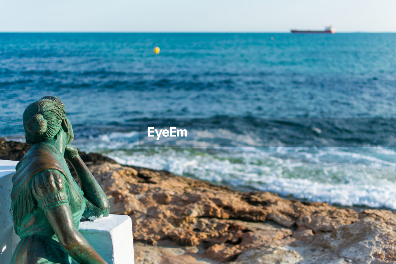 Statue at rock sea shore