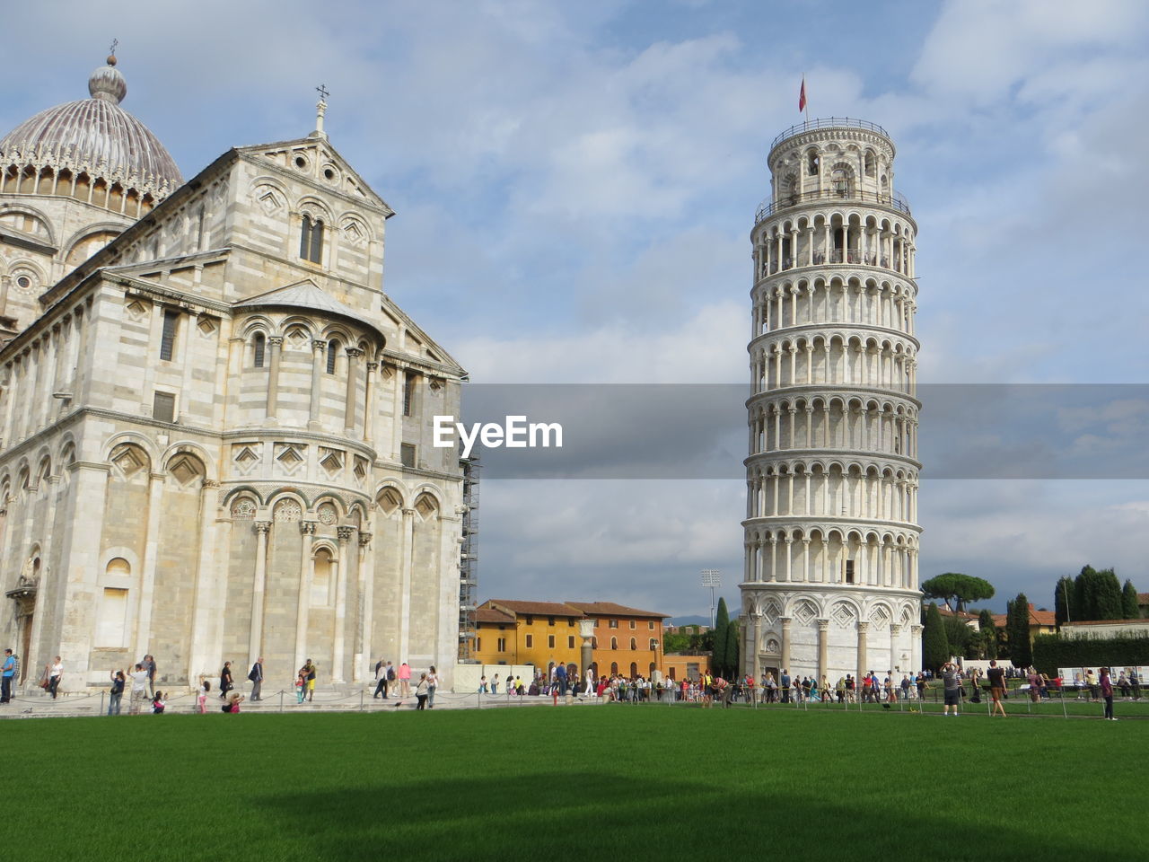 Leaning tower of pisa and cathedral against cloudy sky at piazza dei miracoli