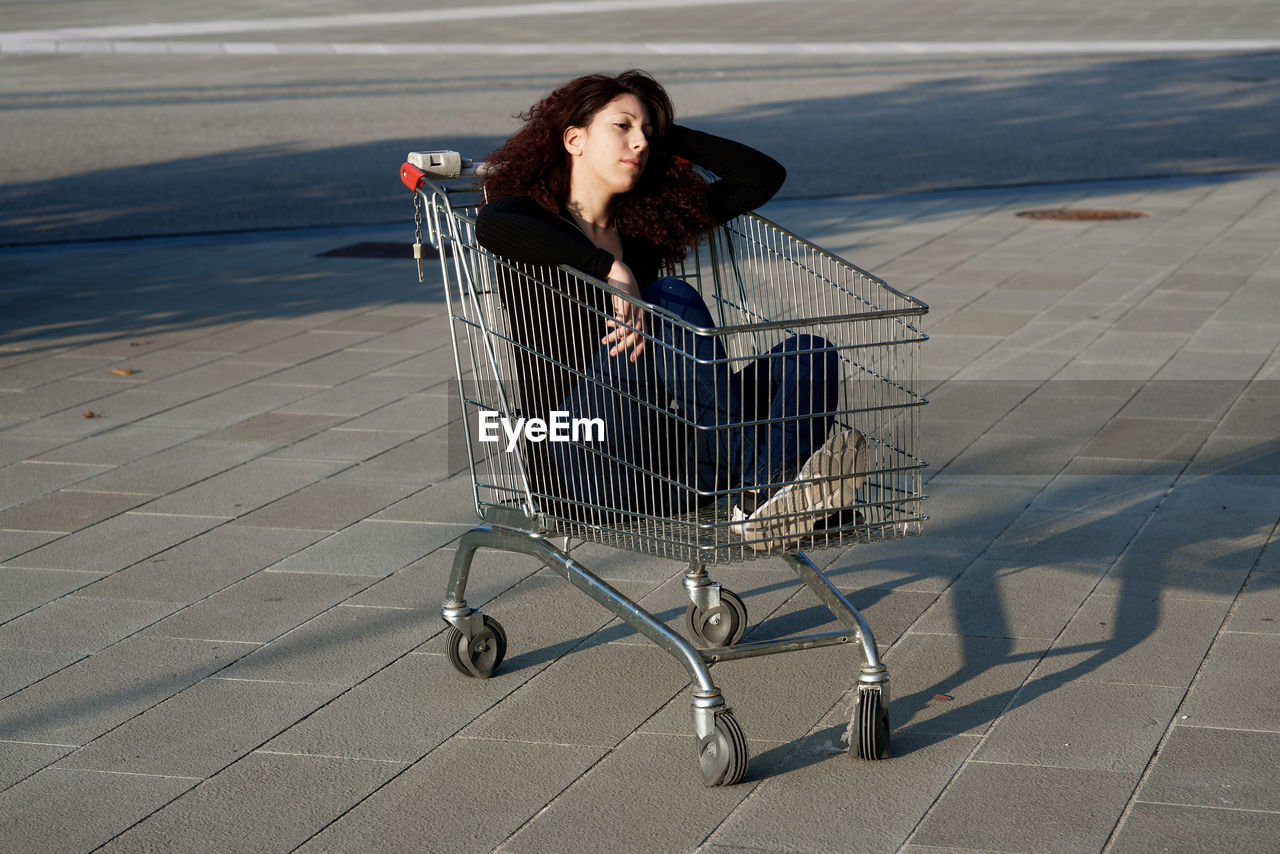 View of woman sitting in shopping cart outdoors