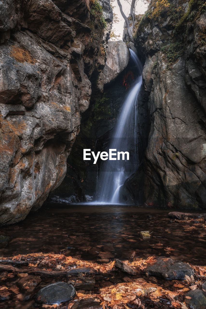 SCENIC VIEW OF WATERFALL AGAINST ROCKS IN FOREST