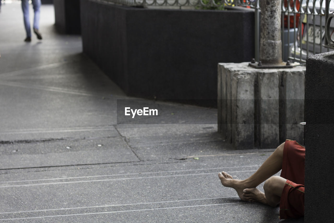 Low section of beggar sitting on footpath