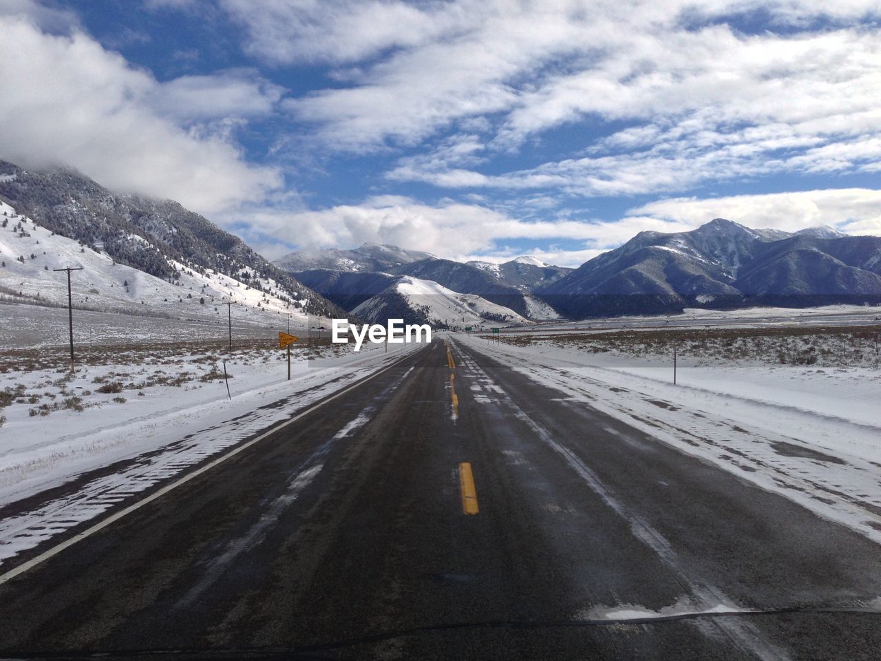 Road leading towards snowcapped mountains against sky