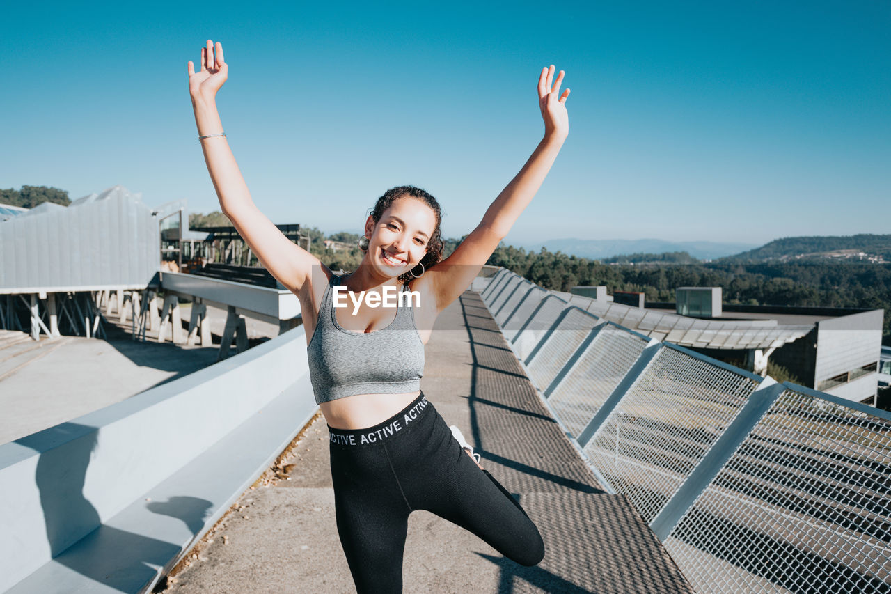 full length of young woman exercising against clear blue sky