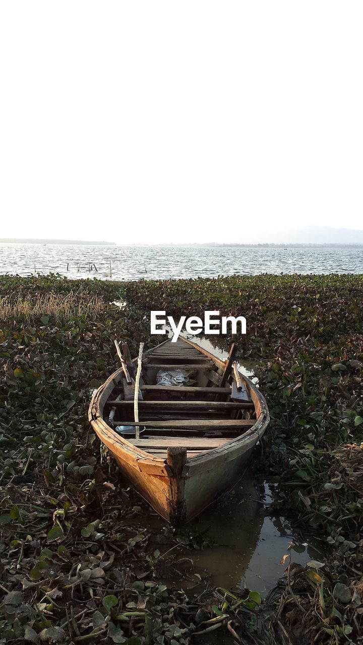 Boat moored at sea shore against clear sky