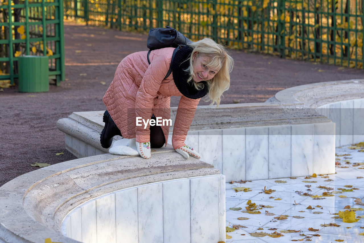 WOMAN SITTING ON RAILING BY SNOW