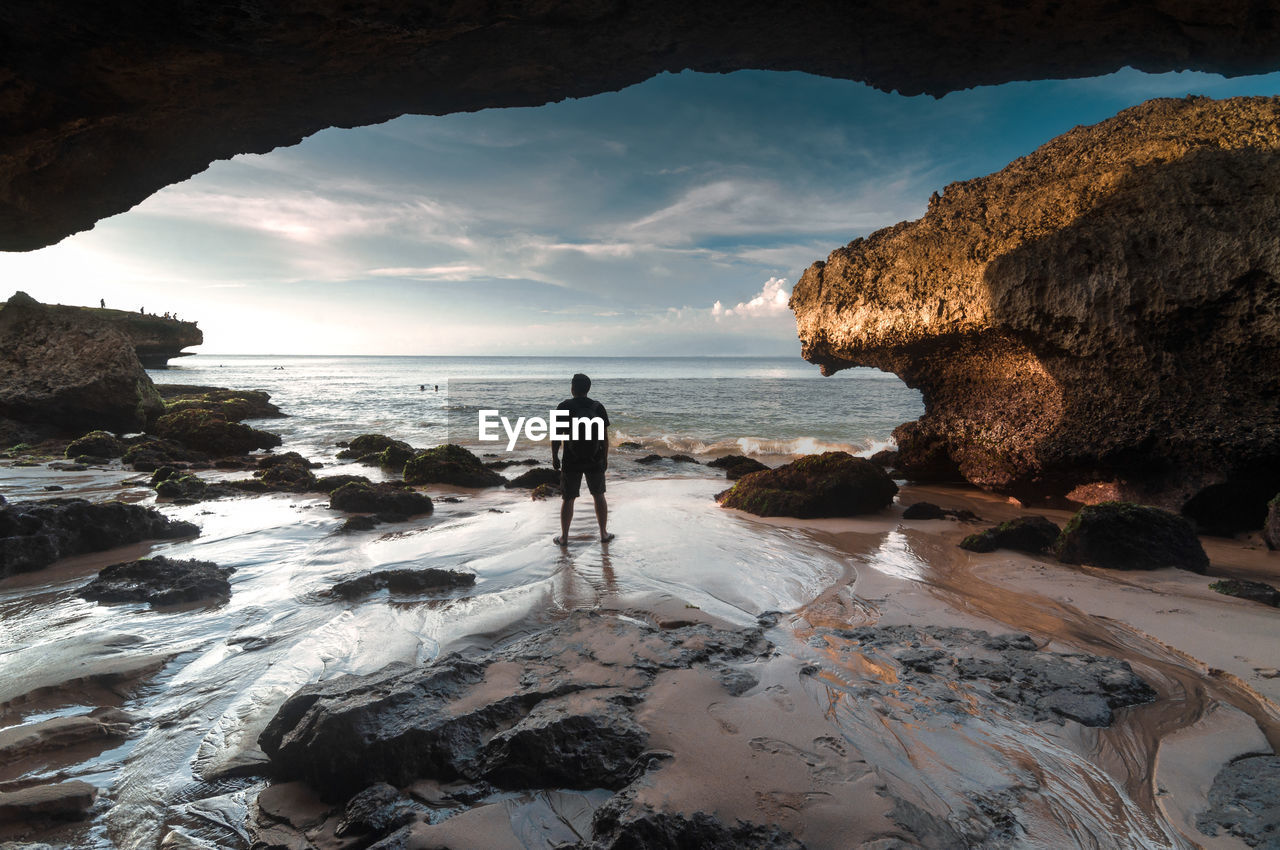 Rear view of backpacker looking at sea while standing on shore